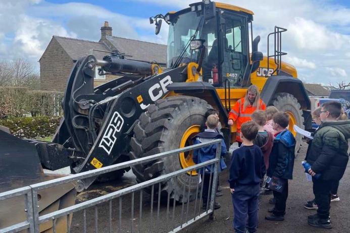 Jemima Colclough from Tarmac shows children one of the loading shovels used to quarry limestone at Tunstead