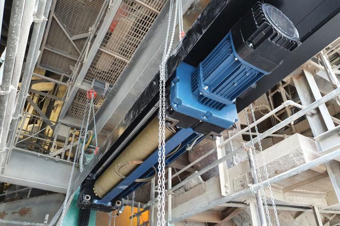 Ten-tonne SWL electric-powered wire-rope hoist unit being lifted into final position at a 60m height by Hoist & Winch