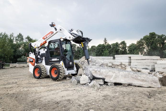 A Bobcat S86 R-series skid-steer loader with breaker attachment in a concrete demolition application