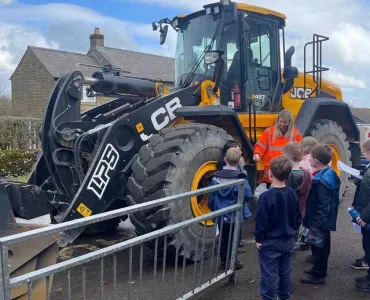 Jemima Colclough from Tarmac shows children one of the loading shovels used to quarry limestone at Tunstead