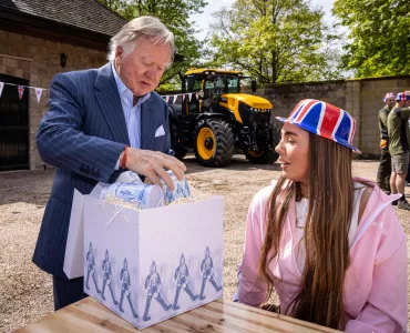 Lord Bamford presents one of the first Coronation gifts to employee Kimberley Brandrick during one of the special celebration lunches