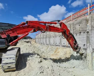 Excavator-mounted Kemroc KR 120 rotary drum cutter profiling the shoring wall before lining it with steel mesh and shotcrete 