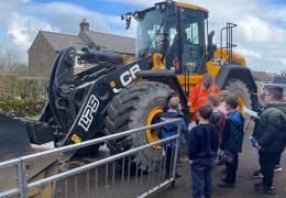 Jemima Colclough from Tarmac shows children one of the loading shovels used to quarry limestone at Tunstead