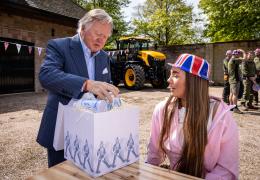Lord Bamford presents one of the first Coronation gifts to employee Kimberley Brandrick during one of the special celebration lunches
