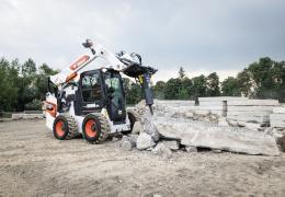 A Bobcat S86 R-series skid-steer loader with breaker attachment in a concrete demolition application