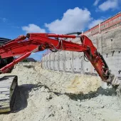 Excavator-mounted Kemroc KR 120 rotary drum cutter profiling the shoring wall before lining it with steel mesh and shotcrete 